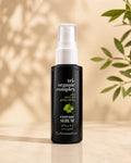 A bottle of Chromastics Tri-Organic Complex Extreme Serum, featuring a matte black bottle and a white spray nozzle, set against a warm beige background with soft leaf shadows and green leaves on the side.