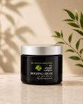 A jar of Chromastics Tri-Organic Complex Molding Cream sits on a light stone surface with a beige background, featuring soft leaf shadows and green plant leaves framing the scene.